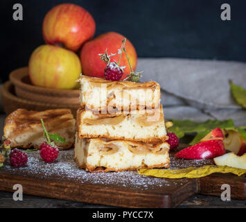 square pieces of apple pie are stacked on a brown wooden board, sponge cake Stock Photo