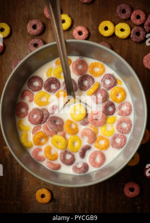 children's dry multi-colored flakes with milk on a wooden table. Stock Photo