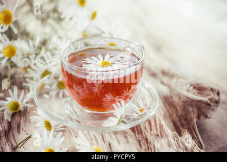 A clear Cup of medicinal chamomile tea on an old wooden table. Health and healthy lifestyle concept. Stock Photo