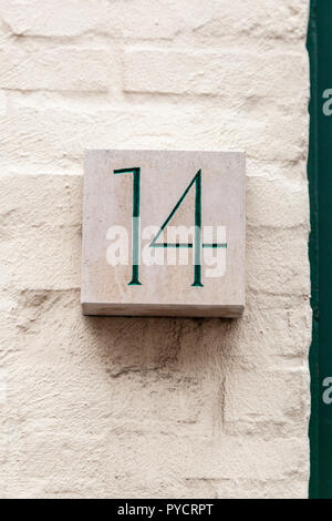 House number fourteen 14 painted green carved in white stone glued to bricks in Sweden Stock Photo