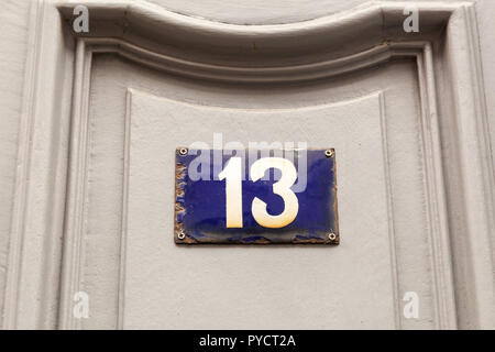 House number thirteen 13 on enamel plaque in black and white on a taupe door from Sweden Stock Photo