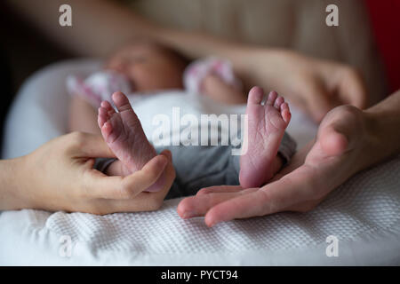 Young couple holding newborn child feet with palms, conceptual image. Stock Photo