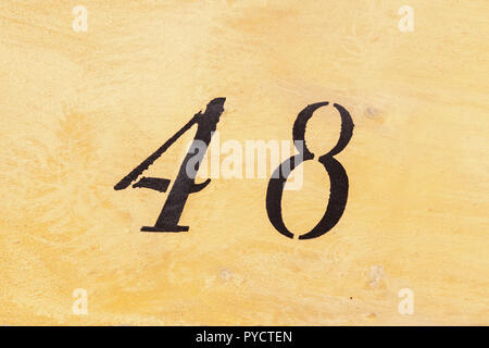 House number forty-eight 48 painted black on yellow render in stylised cursive font from Sweden Stock Photo