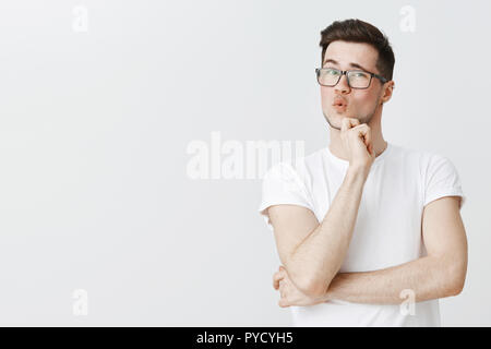 Guy checking out something cool whistling from impression and amazement expressing surprise and delight folding lips holding hands on chin at raising eyebrow from surprise and interest Stock Photo