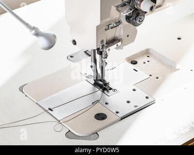 workshop of making textile and leather travel bag - thread in the needle of industrial leather sewing machine close up Stock Photo