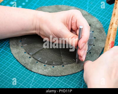 workshop of making the leather bag for jewelry - craftsman makes perforation in the stitched pouch by punch Stock Photo