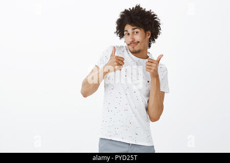 I am alright. Portrait of chill and carefree good-looking male friend with dark skin and afro hairstyle shrugging and showing thumbs up being indifferent to what choice girlfriend make, smiling Stock Photo