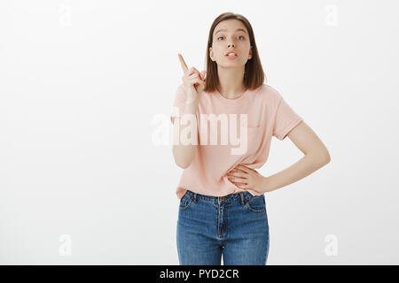 Girl scolds brother, giving directions. Attractive smart smart woman holding hand on waist and shaking index finger while shame sibling for bad behaviour, posing over gray background Stock Photo