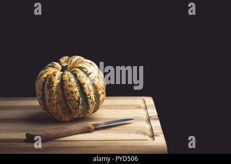 Pumpkin and knife on a wooden cutting board Stock Photo