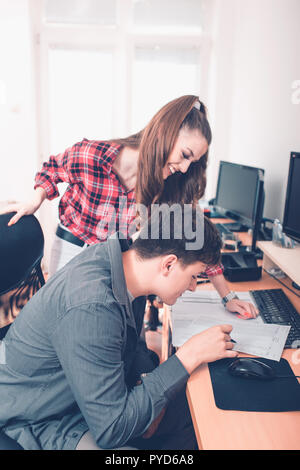 Two young coworkers people talking about documents in office. Stock Photo