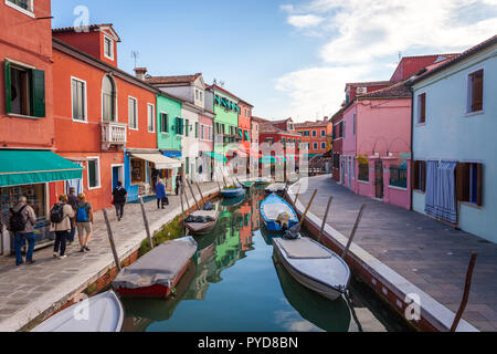 Burano, Italy - October 2018: Tourists walk around the colorful fishermen's houses in Burano on a clear day Stock Photo