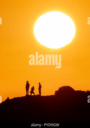 26/10/18: Cyprus:  Tourists view the setting sun from the top of Petra tou Romiou ("Rock of the "Roman") also known as Aphrodite's Rock, near Paphos Stock Photo