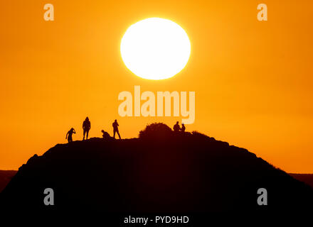 26/10/18: Cyprus:  Tourists view the setting sun from the top of Petra tou Romiou ("Rock of the "Roman") also known as Aphrodite's Rock, near Paphos Stock Photo