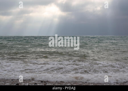 Light through the clouds falling on the sea. Stock Photo