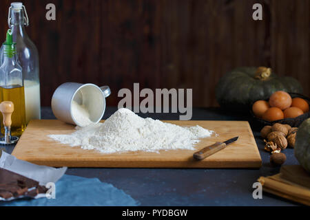 Baking Ingredients Eggs Pumpkin Butter Milk Nuts Flour On A Wooden Table Against A Dark Background Cope space Stock Photo