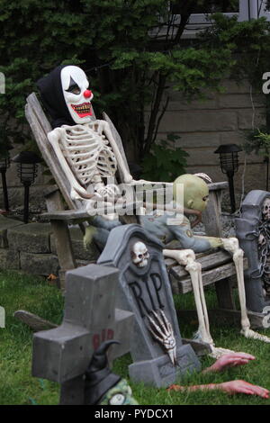 Scary clown face with a skeleton body and a zombie baby on her lap as creative halloween lawn decorations. Stock Photo