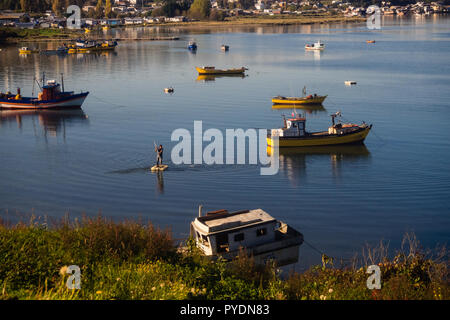 Fisherman rows to his fishing boat in Quellón, Chiloe Island In Chile Stock Photo