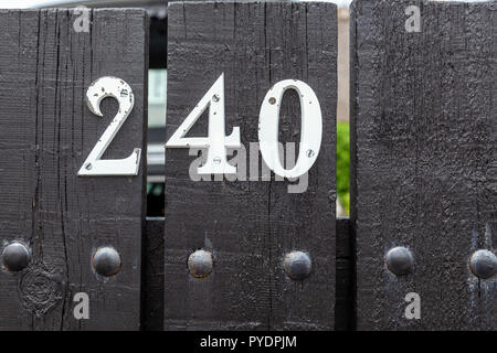 House number two hundred and forty 240 in  cut out metal, weathered and peeling white paint in designer font from Sweden Stock Photo