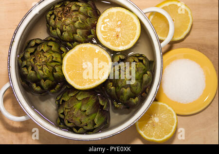 artichokes cooked with lemon and salt in the pot with water Stock Photo