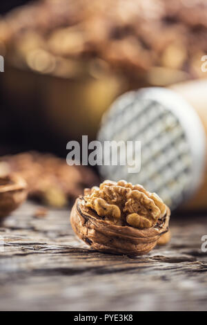 Close-up walnut kernel and whole walnuts on old wooden table. Stock Photo
