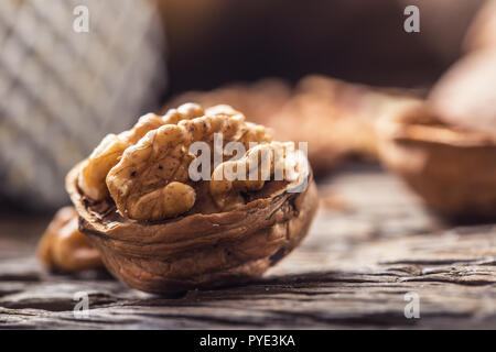 Close-up walnut kernel and whole walnuts on old wooden table. Stock Photo