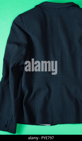 Fragment of the back of a black female jacket with stripes on a green background Stock Photo