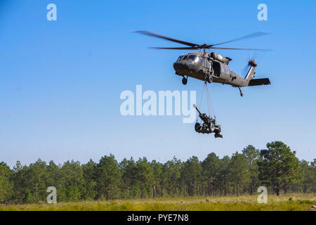 A UH-60 Blackhawk helicopter piloted by aviators from Company C, 2-82 Aviation Regiment, 82nd Combat Aviation Brigade sling-loads a M119A3 Howitzer belonging to Alpha Battery, 1st Battalion, 319th Airborne Field Artillery Regiment, 3rd Brigade Combat Team, 82nd Airborne Division during an air assault and live-fire exercise held Oct. 24, 2018 on Fort Bragg, North Carolina.  The operation tested the paratroopers’ and aviators’ ability to integrate their capabilities while demonstrating their technical expertise and tactical capability to provide lethal fires. Stock Photo