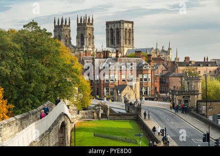 Scenic autumn York cityscape - historic landmarks, medieval walls, sunlit Minster towers, Lendal Bridge & people walking - North Yorkshire, England UK Stock Photo