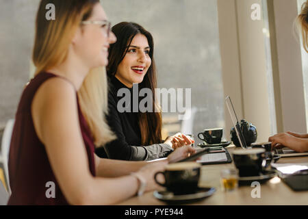 Happy young woman having casual talk during break in meeting. Multi-ethnic businesswomen having break during meeting. Stock Photo