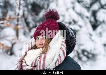 portrait of a young woman in a wintry landscape with warm clothes a red cap and scarf. Stock Photo