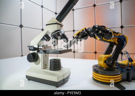 Microscope slide in robot arm and science microscope Stock Photo