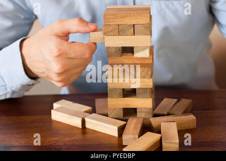 hand of businessman pulling out or placing wood block on the tower Stock Photo