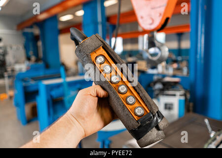 remote control of the crane on production. Workers working with a crane in the warehouse.. the production of ventilation and gutters. Tool and bending equipment for sheet metal. Stock Photo