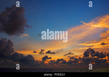 Orange sunset over sea, with dark clouds and rays of light Stock Photo