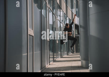 full length view of young man in black clothes jumping in dance Stock Photo