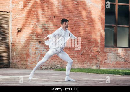 young male dancer in white clothes practicing on street Stock Photo