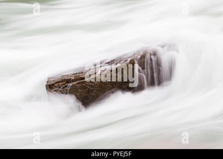 A long exposure close up of rapids flowing over a rock in Niagara Gorge, Canada.  The rapids are amongst the most powerful in the world. Stock Photo