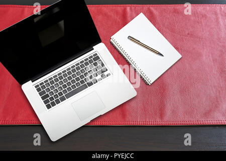 Notepad and notebook laptop on Red leather tablecloth, view from above Stock Photo