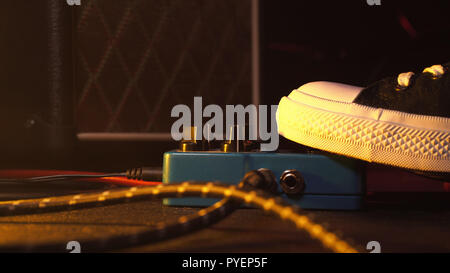 Guitar pedals and footswitch inside recording room. Close up of guitar pedals and musician's foot tapping on it for different sounds. Macro view. Stock Photo