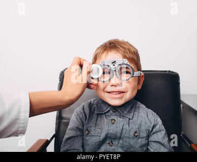 optometrist checking vision of a little cheerful boy using trial frame Stock Photo