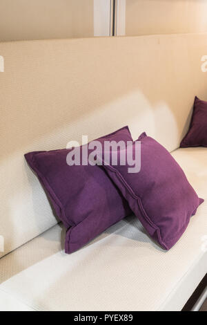 decorative lila pillows on a white couch inside a caravan, switzerland Stock Photo