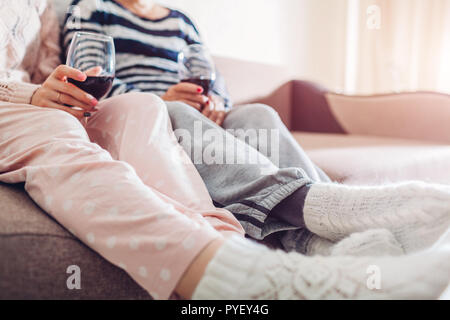 Mother and her adult drinking wine sitting on couch at home. Women talking and relaxing. Family time Stock Photo