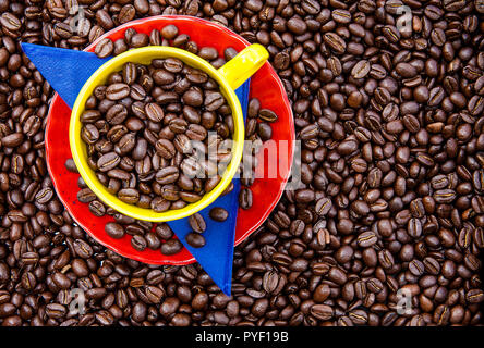 Cup filled with Colombian coffee beans and the colors of the Colombian flag over a background of roasted coffee beans Stock Photo