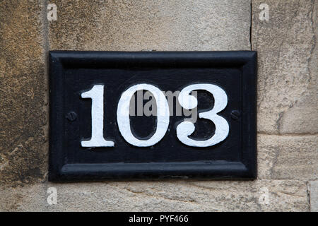 One Hundred and Three Number Sign on Stone Wall Stock Photo