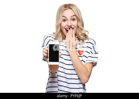 Gorgeous excited woman showing blank screen mobile phone over white background, celebrating victory and success. Very excited, cheering emotion. Stock Photo
