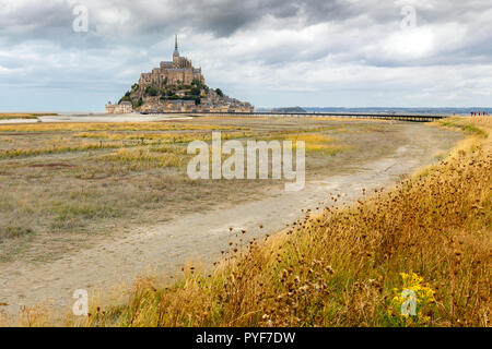 The Mont Saint Michel fortified village and church at low tide in end of summer under a dramatic sky, Normandie, France Stock Photo