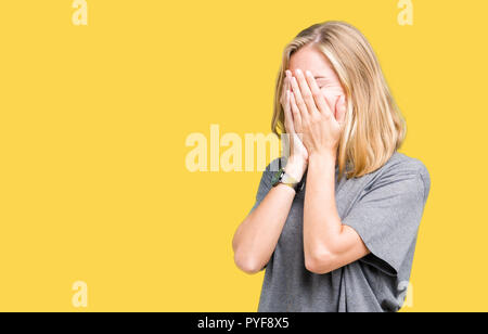 Beautiful young woman wearing oversize casual t-shirt over isolated background with sad expression covering face with hands while crying. Depression c Stock Photo