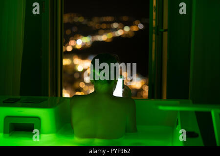 woman in hotel bathroom reading on tablet, Santorini, Greece Stock Photo