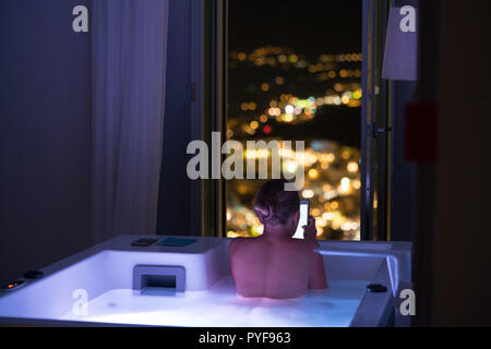 woman in hotel bathroom reading on tablet, Santorini, Greece Stock Photo