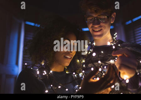 Couple playing with fairy lights at home Stock Photo